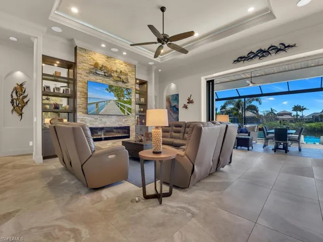 Spacious living area featuring large format tile flooring and a stacked stone accent wall with integrated shelving and fireplace