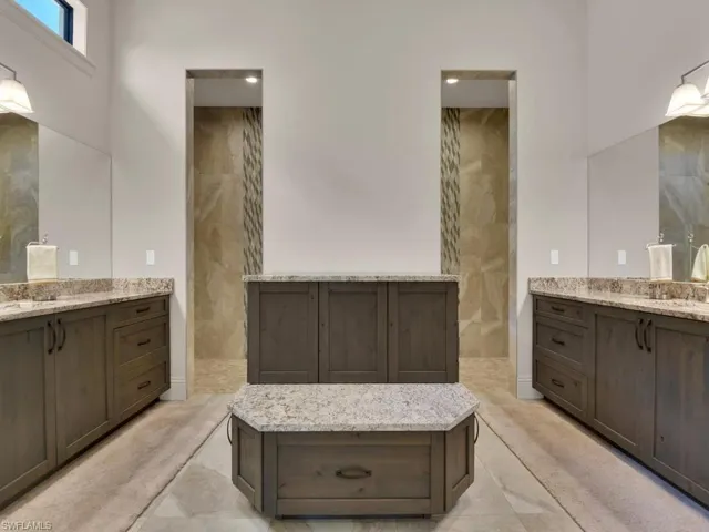 Spacious bathroom featuring dual vanities with granite countertops and wood-finish cabinetry