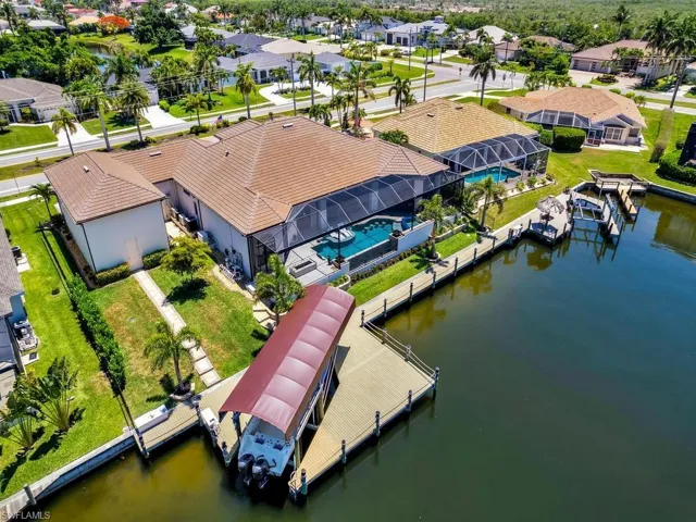 Waterfront property featuring a screened-in pool area, tile roof, and a private dock with a boat lift