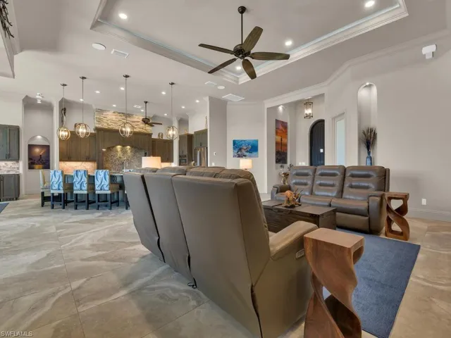 Spacious open-concept living area featuring a tray ceiling with recessed lighting and a ceiling fan