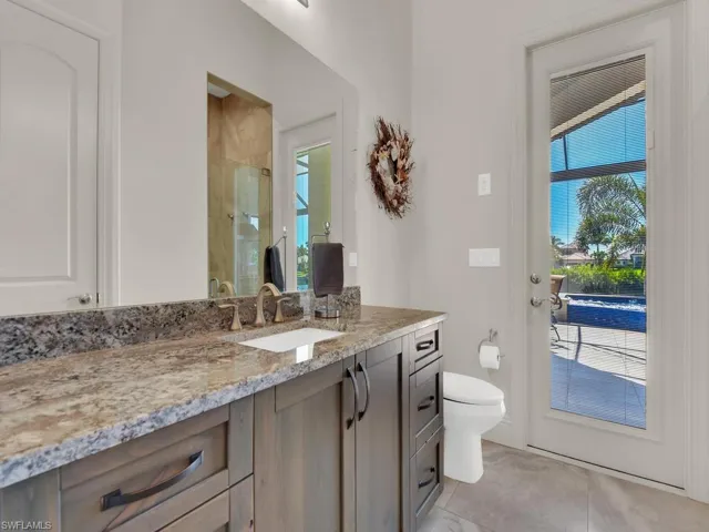Bathroom featuring a single vanity with a granite countertop, undermount sink, and wood-finish cabinetry