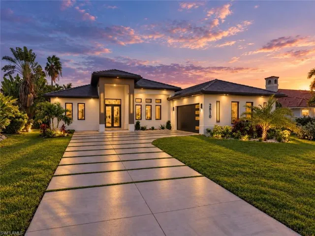 Single-story residence featuring a tile roof, stucco exterior, covered entryway, and a paver driveway with integrated turf ribbons