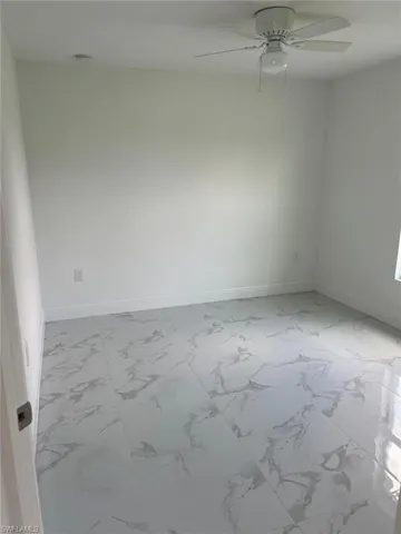 Tiled spare room featuring ceiling fan