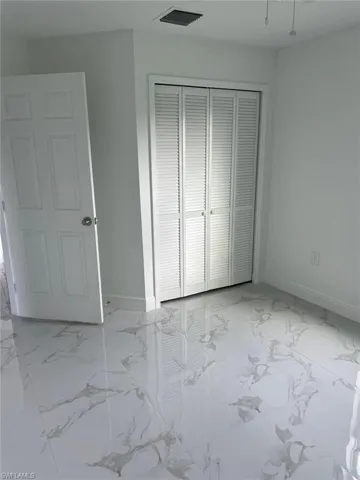 Unfurnished bedroom with a closet and light tile flooring