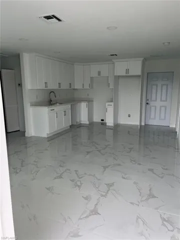 Kitchen featuring sink, white cabinetry, and light tile flooring