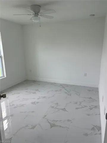 Tiled empty room featuring ceiling fan