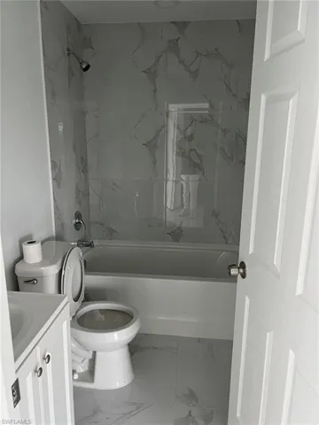 Full bathroom featuring tiled shower / bath combo, vanity, toilet, and tile floors