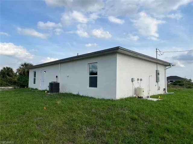 View of side of property with central air condition unit and a lawn