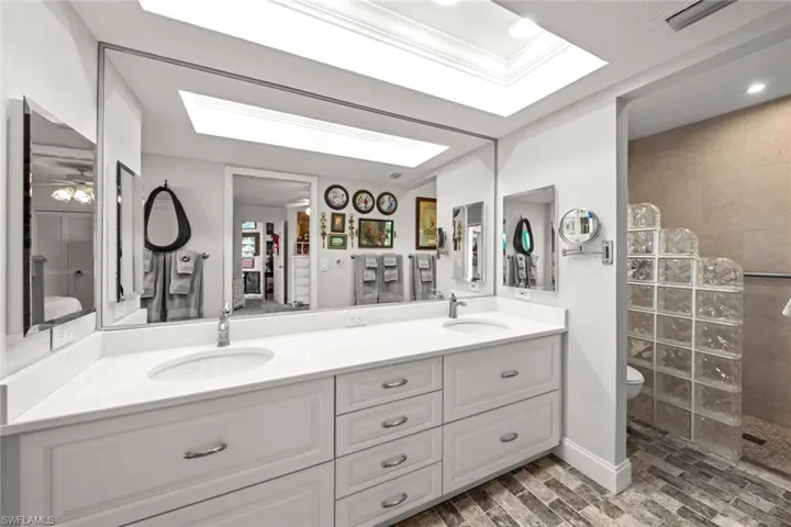 Bathroom featuring vanity, a skylight, hardwood / wood-style flooring, toilet, and a tile shower