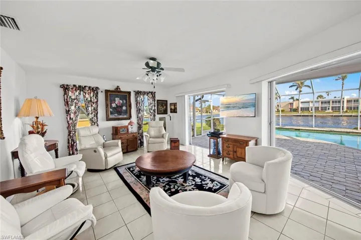 Living room with light tile patterned floors, ceiling fan, and a healthy amount of sunlight