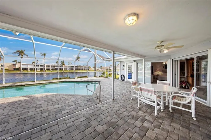 View of swimming pool featuring a patio, a water view, glass enclosure, and ceiling fan