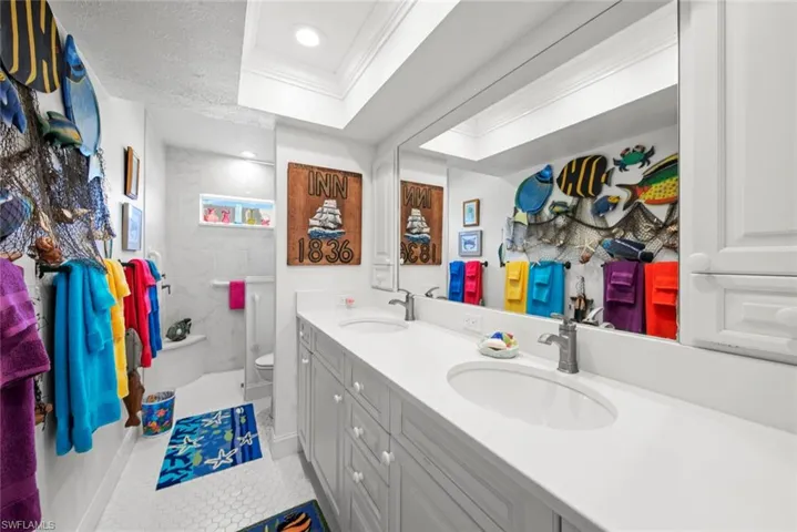 Bathroom with vanity, crown molding, tile patterned flooring, toilet, and a tile shower