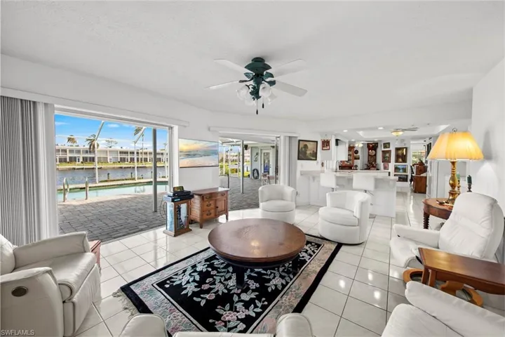 Tiled living room featuring ceiling fan, a water view, and a textured ceiling