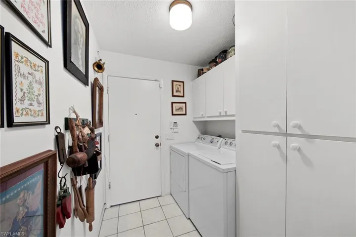 Washroom featuring cabinets, light tile patterned floors, a textured ceiling, and washing machine and dryer