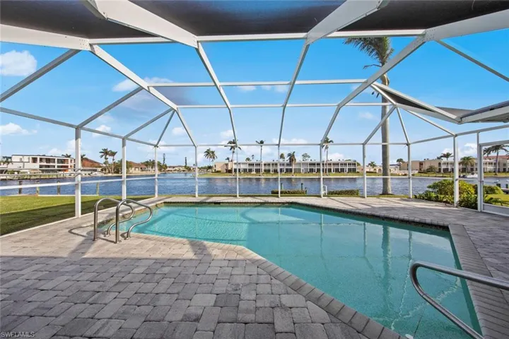View of swimming pool with a lanai, a water view, and a patio