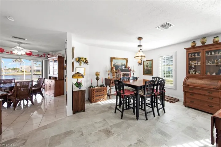 Dining space featuring a textured ceiling, ceiling fan with notable chandelier, a water view, and light tile patterned floors