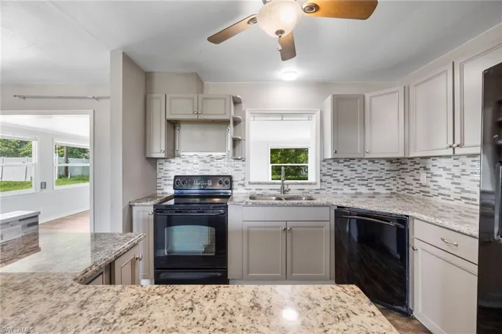 Kitchen featuring black appliances, decorative backsplash, gray cabinetry, and open shelves