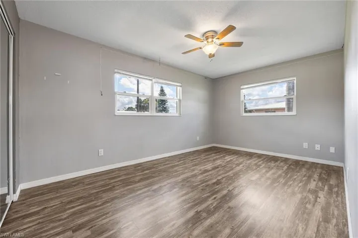 Unfurnished room with dark wood-style flooring, ceiling fan, and a textured ceiling