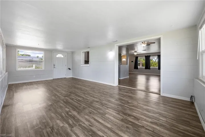 Unfurnished living room with dark wood finished floors, ceiling fan, and wood walls