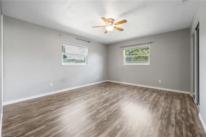 Unfurnished bedroom featuring a closet, dark wood finished floors, and a ceiling fan