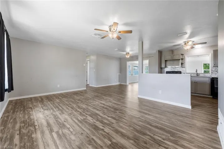 Unfurnished living room featuring dark wood finished floors and baseboards