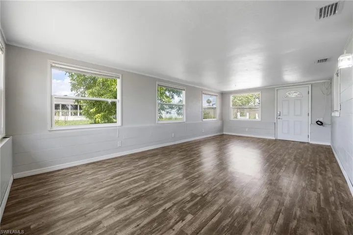 Unfurnished living room featuring concrete block wall and dark wood finished floors