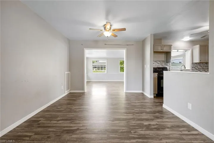 Unfurnished living room featuring a ceiling fan and dark wood-style floors