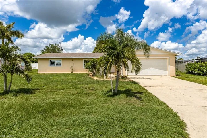 Ranch-style home featuring an attached garage, a front yard, and driveway