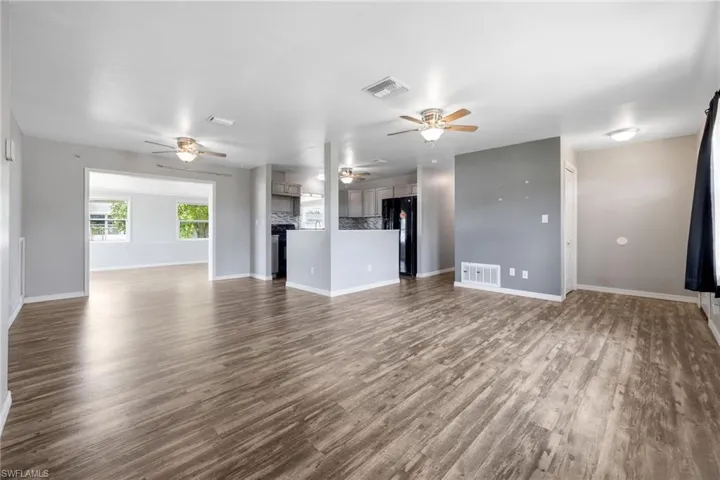 Unfurnished living room with dark wood-type flooring and a ceiling fan
