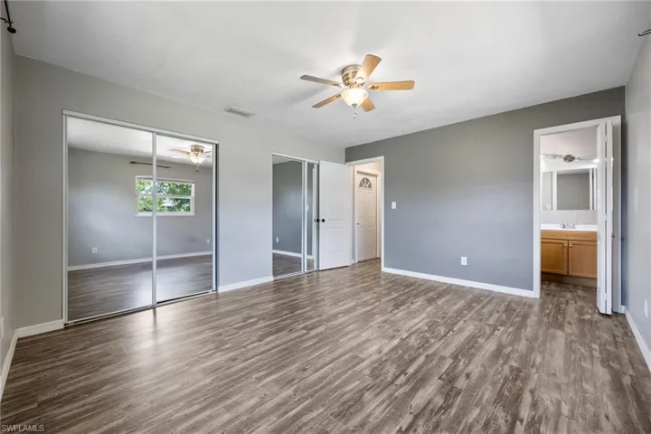 Unfurnished bedroom featuring dark wood finished floors, a ceiling fan, and ensuite bath