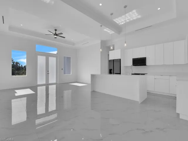 Kitchen featuring stainless steel refrigerator with ice dispenser, a tray ceiling,  decorative light fixtures, and white cabinets
