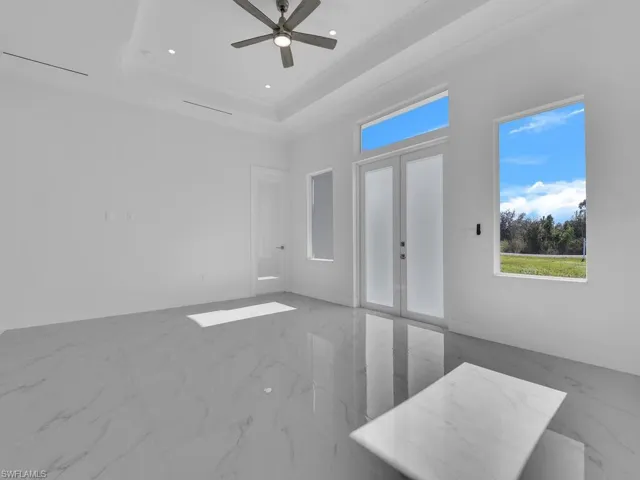 Spare room featuring a raised 10' ceiling, ceiling fan, and french doors