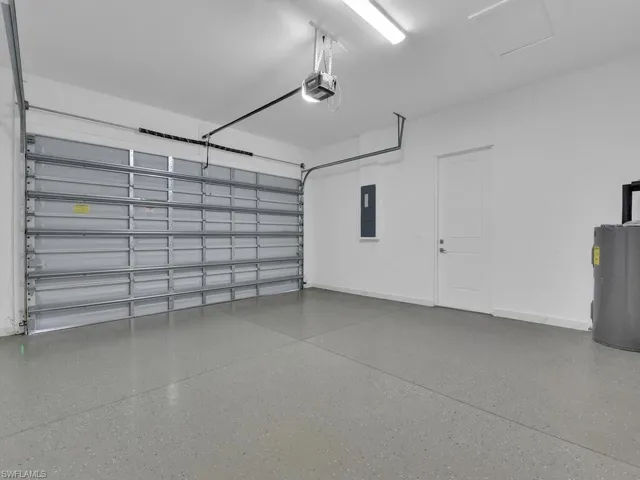 Garage featuring a garage door opener, electric panel, and water heater.