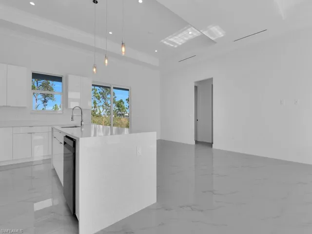 Kitchen featuring pendant lighting, dishwasher, sink, an island with sink, and white custom wood cabinetry
