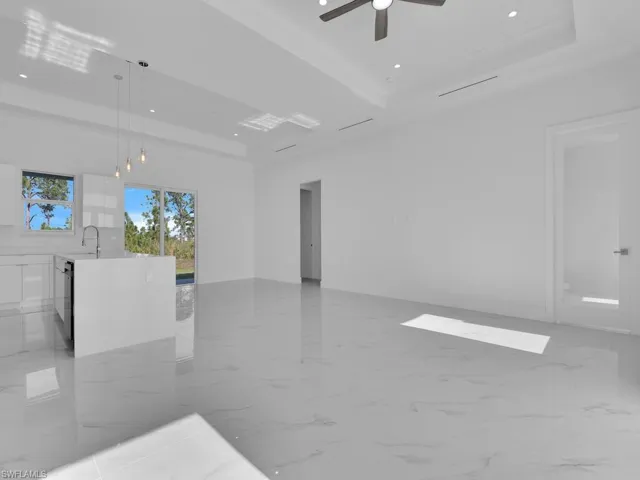 Empty room with a raised ceiling, ceiling fan, and sink.