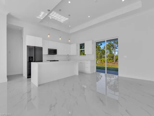 Kitchen featuring a center island, stainless steel refrigerator with ice dispenser,  decorative light fixtures, and white cabinets