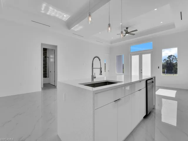 Kitchen featuring a tray ceiling, sink, diswasher, white cabinets, and pendant lighting