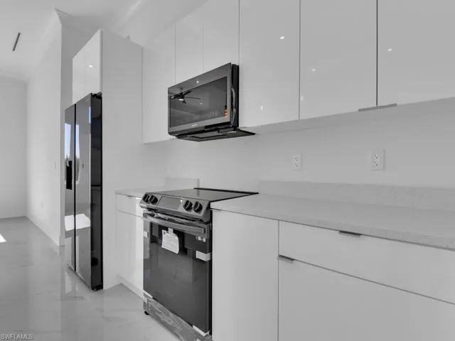 Kitchen with custom wood white cabinetry, ceiling fan, and stainless steel appliances