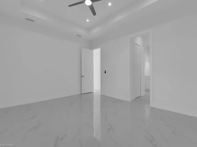 Primary bedroom featuring a tray ceiling and ceiling fan.