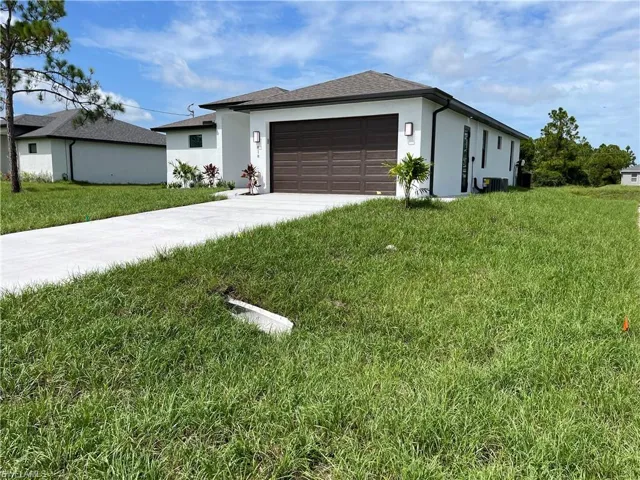 View of front of house with driveway, stucco siding, a garage, a front lawn, and roof with shingles