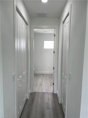 Hallway featuring dark wood-style floors and baseboards