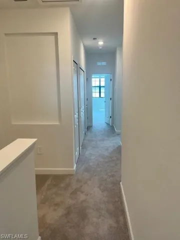 Hallway featuring carpet and baseboards