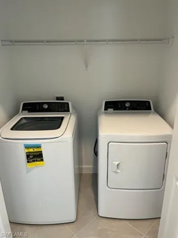 Washroom with washer and clothes dryer and light tile patterned floors