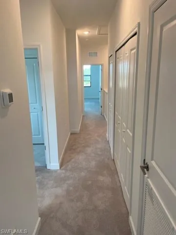 Hallway featuring carpet floors and baseboards
