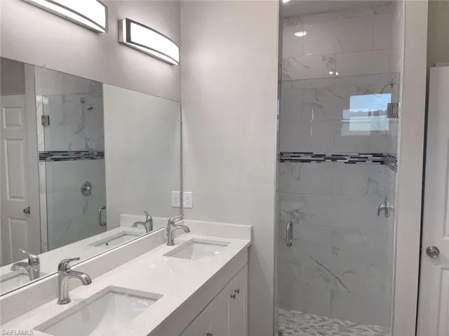 Bathroom featuring double vanity and an enclosed shower