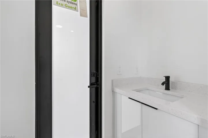 Bathroom vanity with a white rectangular undermount sink, speckled countertop, and a matte black single-handle faucet