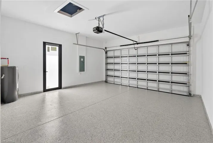 Spacious garage featuring an epoxy-coated concrete floor, automatic overhead door, and a dedicated utility entrance