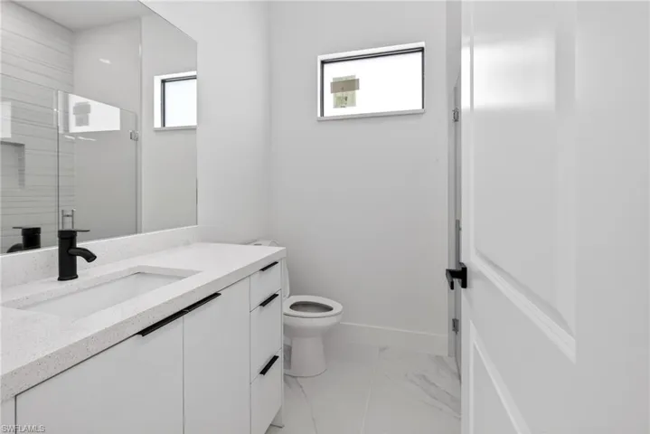 Bathroom featuring a white vanity with an integrated sink, black hardware, a matte black faucet, and a large wall mirror