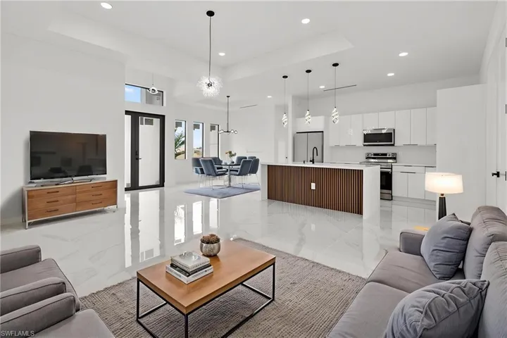 Open-concept living space featuring high ceilings, white tile flooring, and recessed lighting