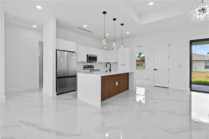 Modern kitchen with a white quartz island featuring a wood-panel accent, stainless steel appliances, recessed lighting, and large format polished tile flooring